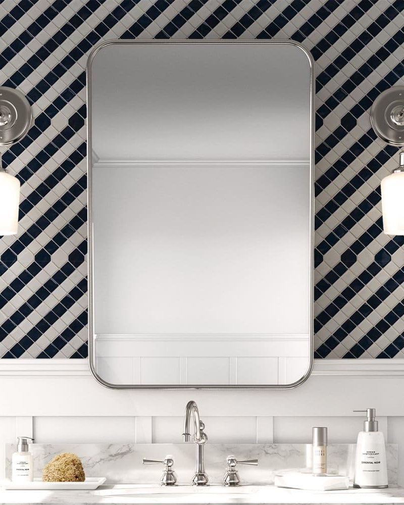 Bathroom vanity with a rectangular mirror, flanked by wall-mounted lights, above a marble countertop.