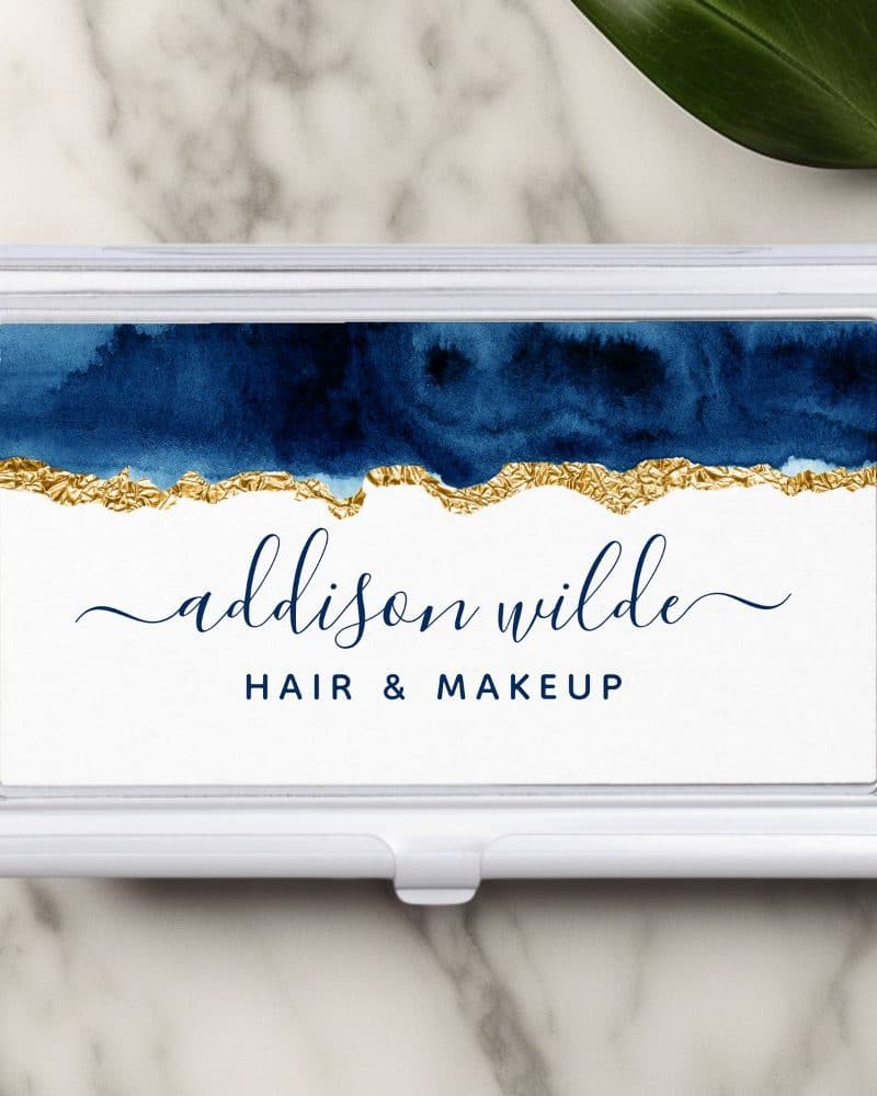 Silver business card holder with a navy blue and gold watercolor design. The name Addison Wilde, Hair & Makeup, is printed below.