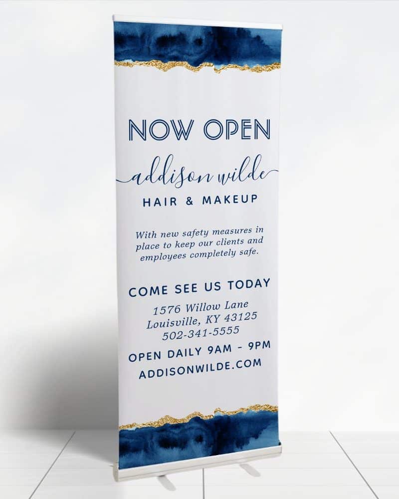 A retractable banner announcing the grand opening of Addison Wilde Hair & Makeup.