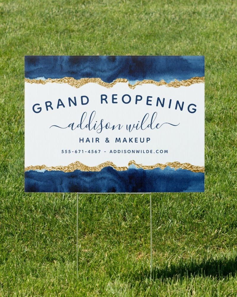 Grand reopening sign for Addison Wilde Hair & Makeup. The sign is navy blue and white with gold accents.