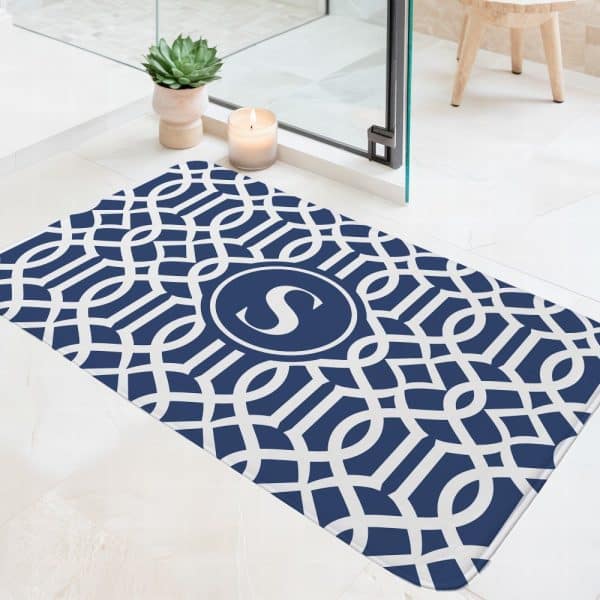 Navy Blue Bath Mat With A White Geometric Pattern And A Centered Monogram Of The Letter S.