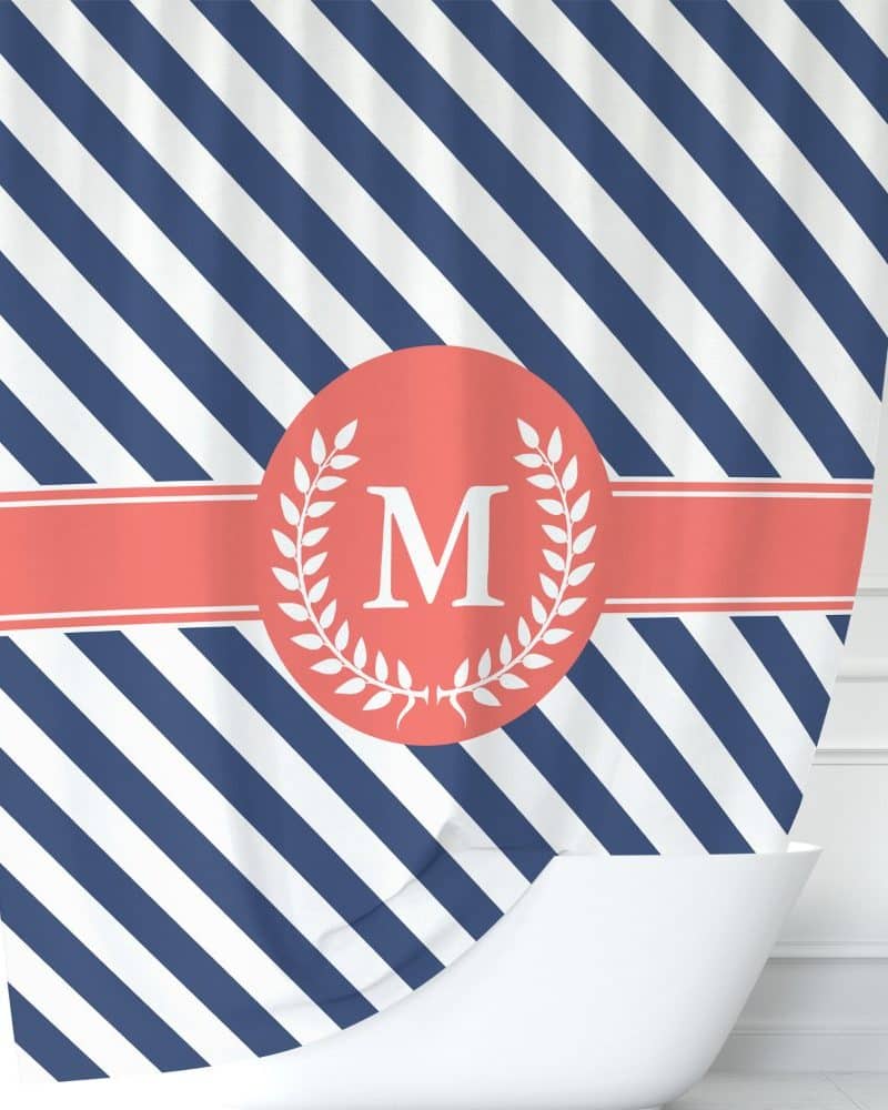 Navy and white diagonal striped shower curtain with a coral circle and laurel wreath featuring the letter M.
