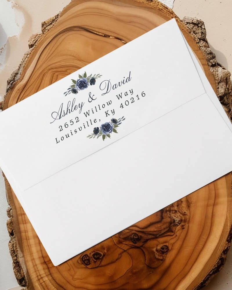 A white envelope with a return address featuring Ashley & David's name and Louisville, Kentucky address, decorated with a floral design.