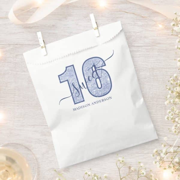 White Party Favor Bag With A Blue Glitter Sixteen And The Words Sweet Sixteen. The Name Madison Anderson Is Printed Below.