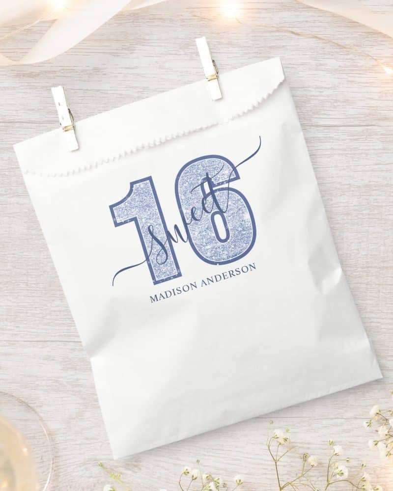 White party favor bag with a blue glitter sixteen and the words Sweet Sixteen. The name Madison Anderson is printed below.