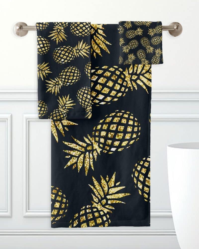 Black bath towels with a gold glitter pineapple pattern.