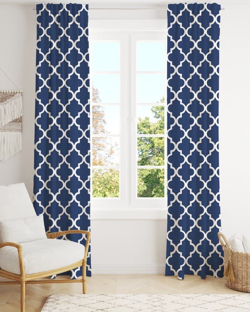 Navy blue curtains with a white quatrefoil pattern hang on a window.