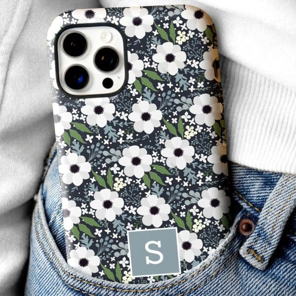 Phone Case In A Jeans Pocket, Featuring A Dark Background With A Repeating Pattern Of White Flowers And Green Leaves, And A Gray Square With The Letter S.