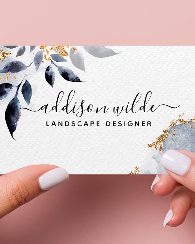 Business card for Addison Wilde, Landscape Designer, featuring blue watercolor leaves and gold accents.