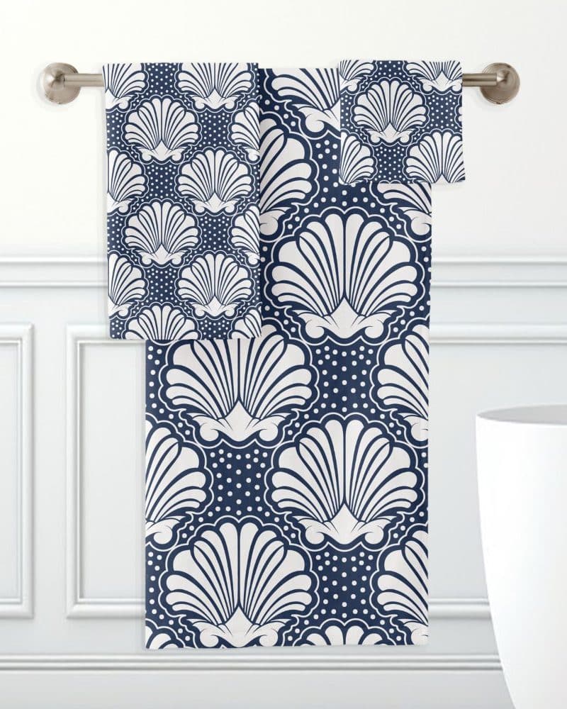 Navy blue and white hand towels with a seashell pattern hanging on a towel bar.