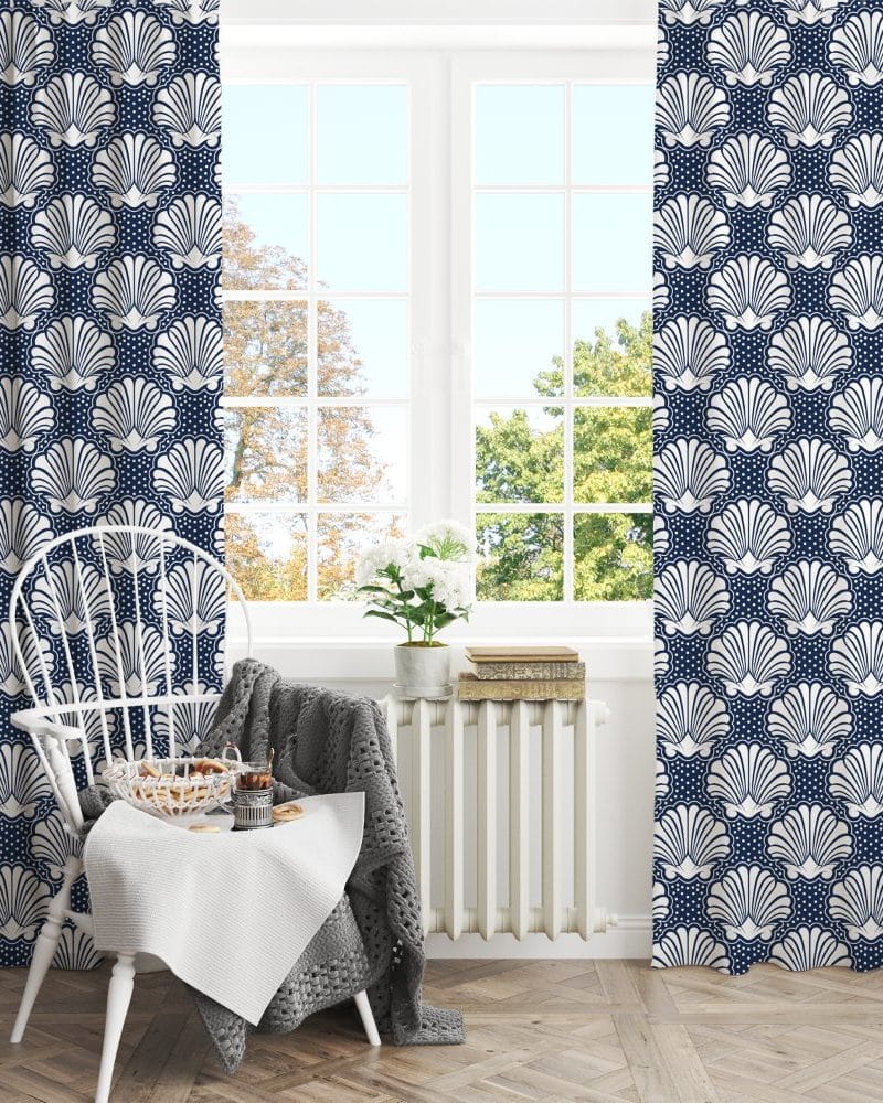 Navy blue curtains with a white seashell pattern hang in a window.