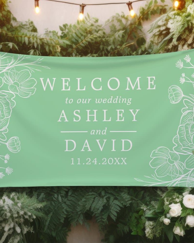 Light green wedding welcome banner with white floral designs and the names Ashley and David, and wedding date.