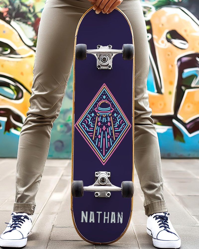 Person holding a dark purple skateboard with a neon design of a UFO and the name Nathan.