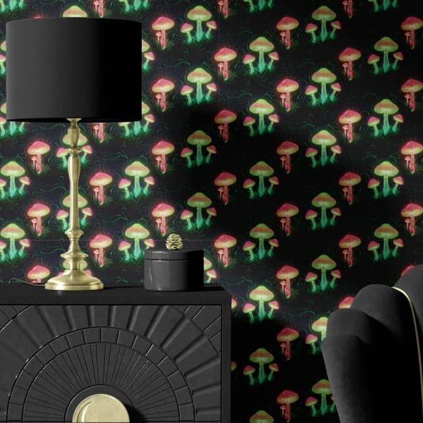 A Dark Gold Lamp Sits On A Black Dresser Against A Wall Covered In Neon Pink And Green Mushroom Wallpaper.