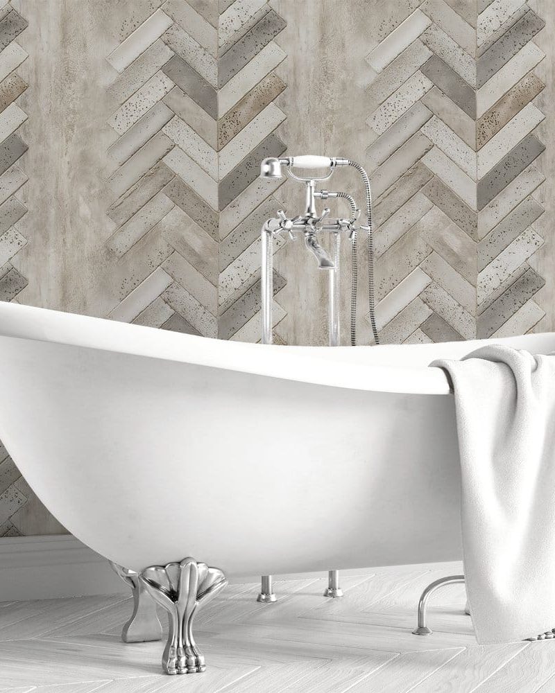 White clawfoot bathtub in front of a herringbone patterned wall.