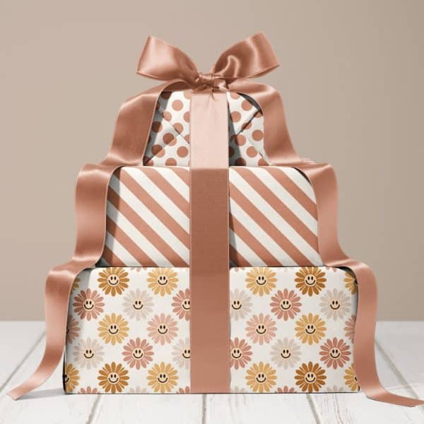 Stack Of Three Gifts Wrapped In Brown And Cream Paper With Different Patterns, Tied With A Large Brown Ribbon.