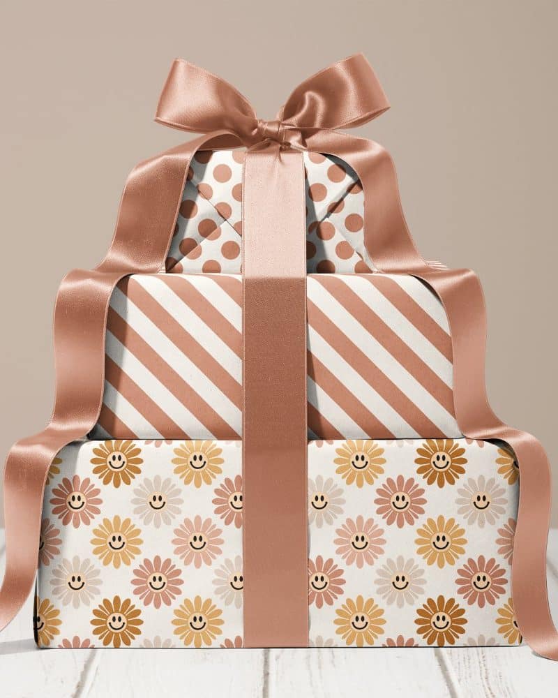Stack of three gifts wrapped in brown and cream paper with different patterns, tied with a large brown ribbon.