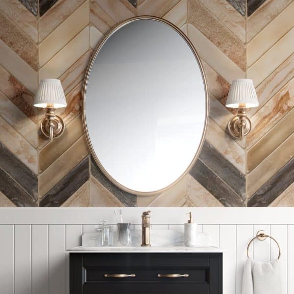 Oval Mirror Above A Bathroom Vanity With Marble Countertop And Dark Cabinetry.