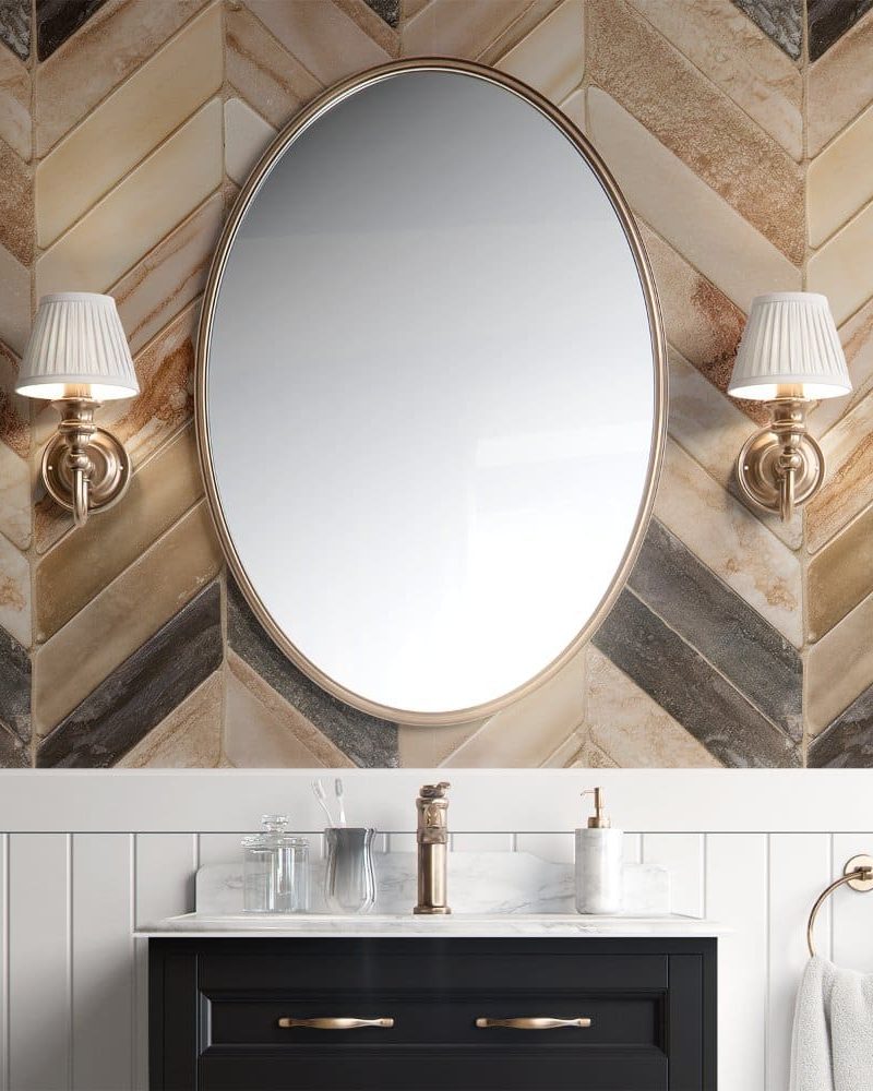 Oval mirror above a bathroom vanity with marble countertop and dark cabinetry.