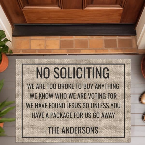 A Tan Doormat With Black Text Reading No Soliciting And A Humorous Message From The Andersons Family.