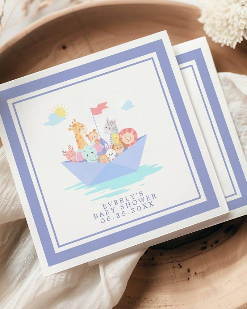 Baby shower invitation featuring a paper boat filled with cartoon animals.