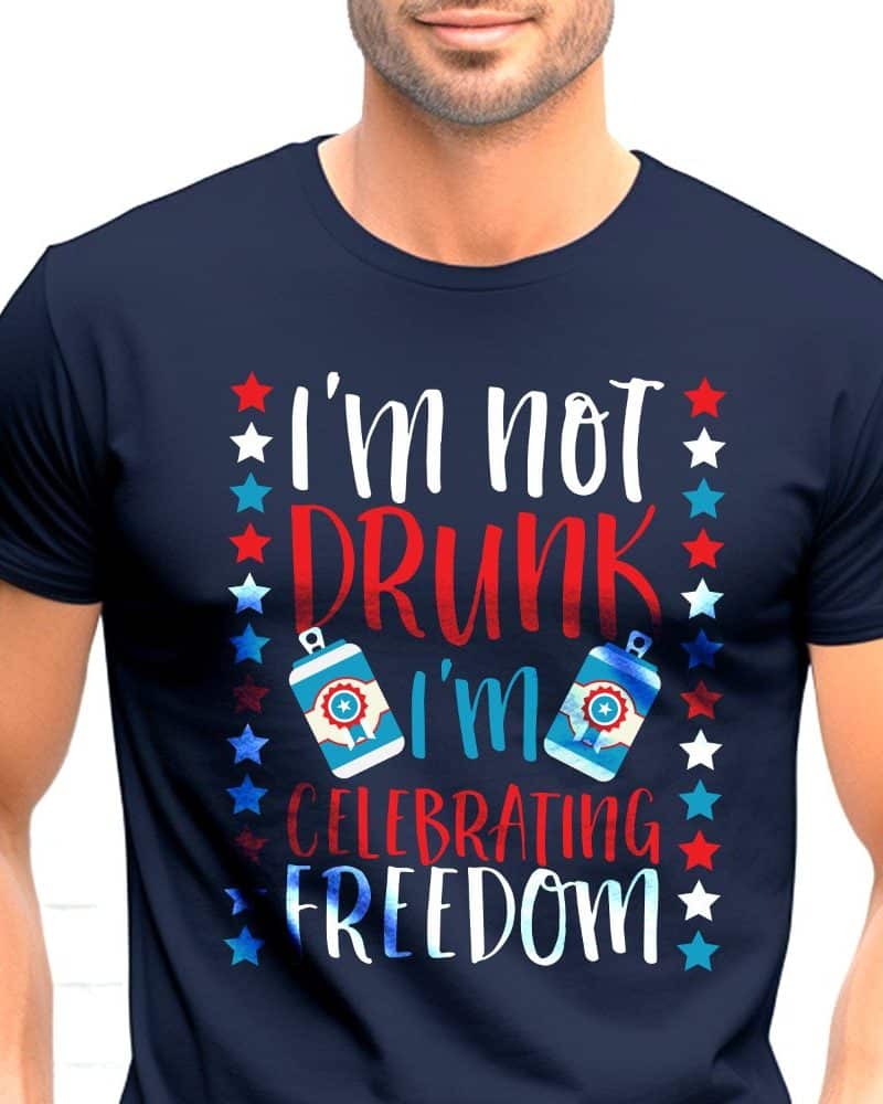 Person wearing a navy blue t-shirt that says Im not drunk Im celebrating freedom, with stars and beer can graphics.