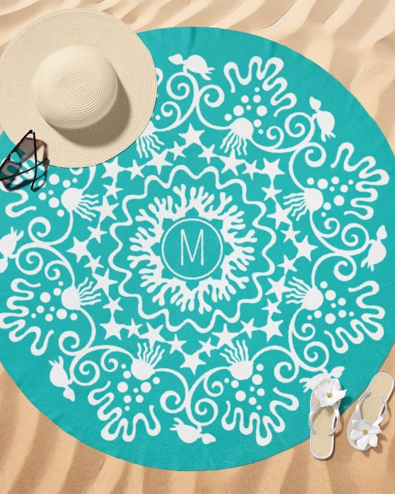 Teal round beach towel with a white mandala design and the initial M in the center.