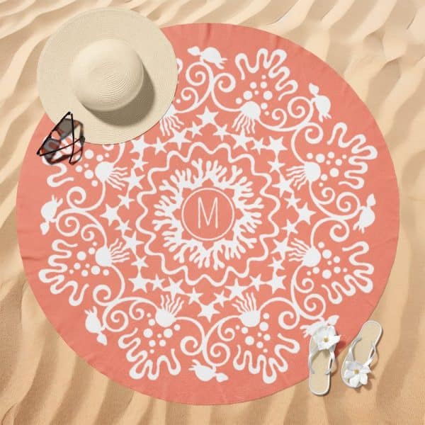 Coral-Colored Round Beach Towel With A White Mandala Design And A Monogram In The Center.