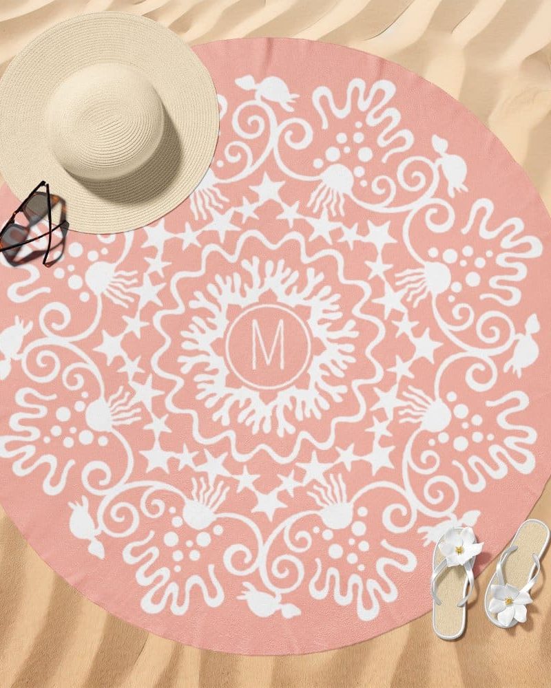 Pink round beach towel with a white mandala design and initial M in the center.