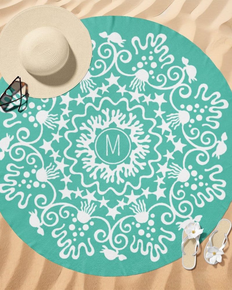 Teal round beach towel with a white mandala design and a central monogram.