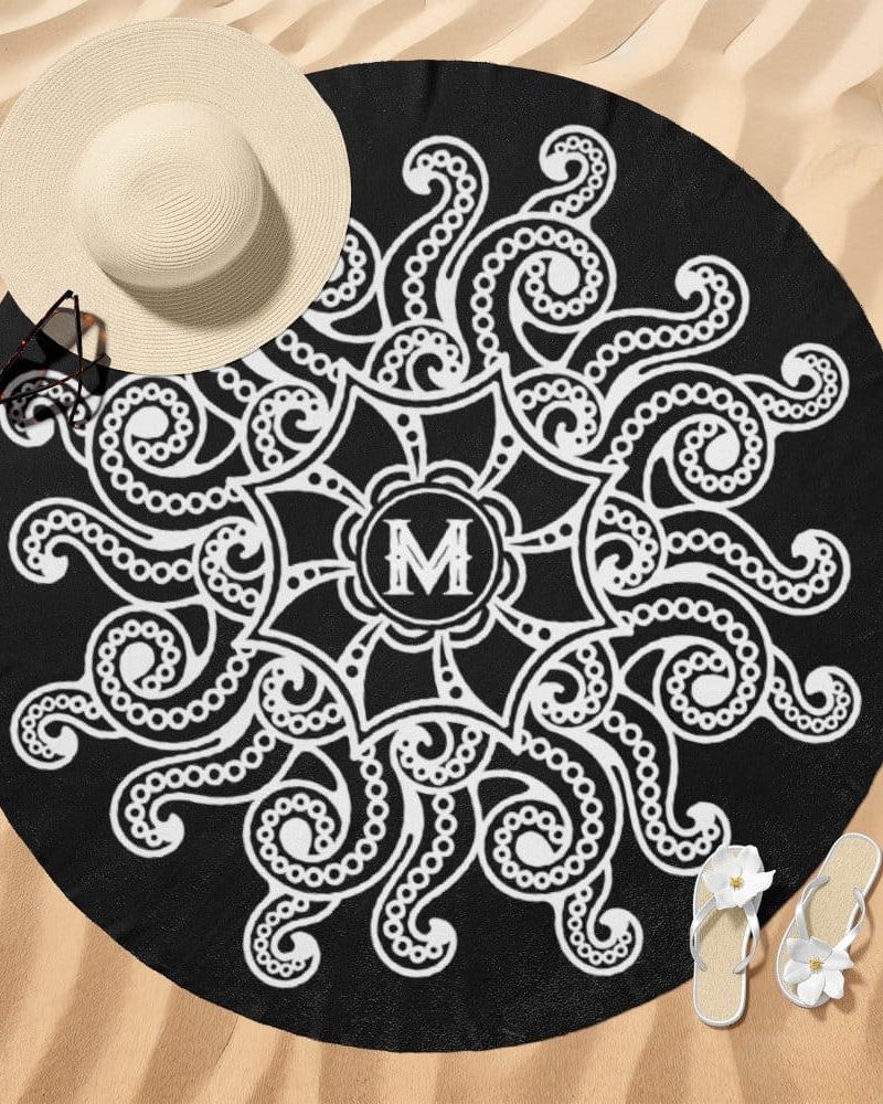 Black round beach towel with a white mandala design featuring an initial M in the center.