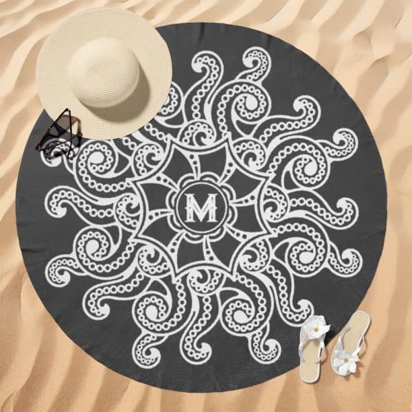 Dark Gray Round Beach Towel With A White Mandala Design Featuring The Letter M In The Center.
