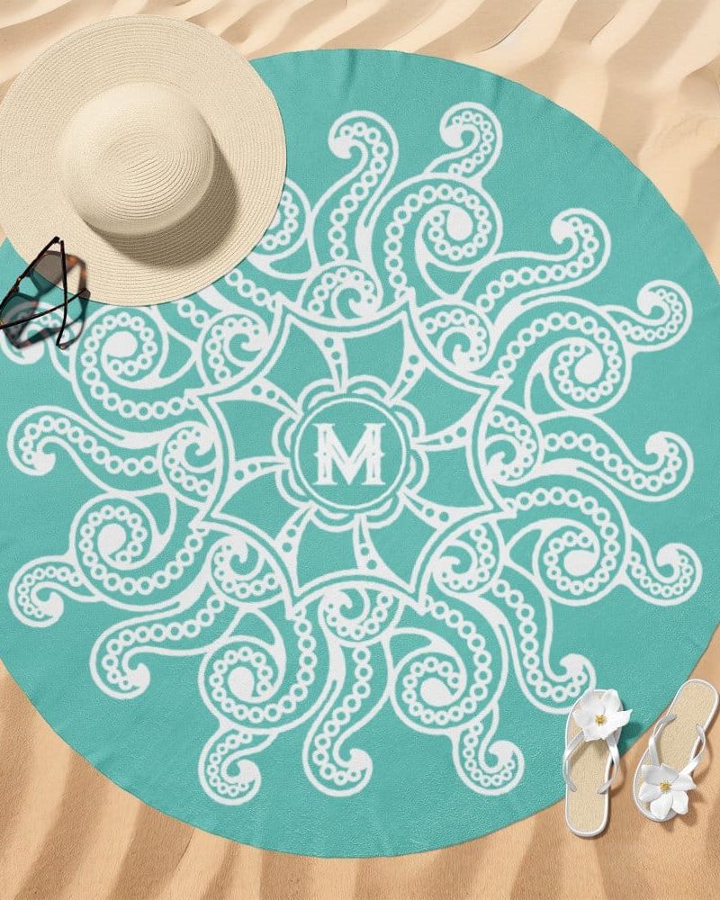 Teal round beach towel with a white mandala design and a monogrammed M in the center.