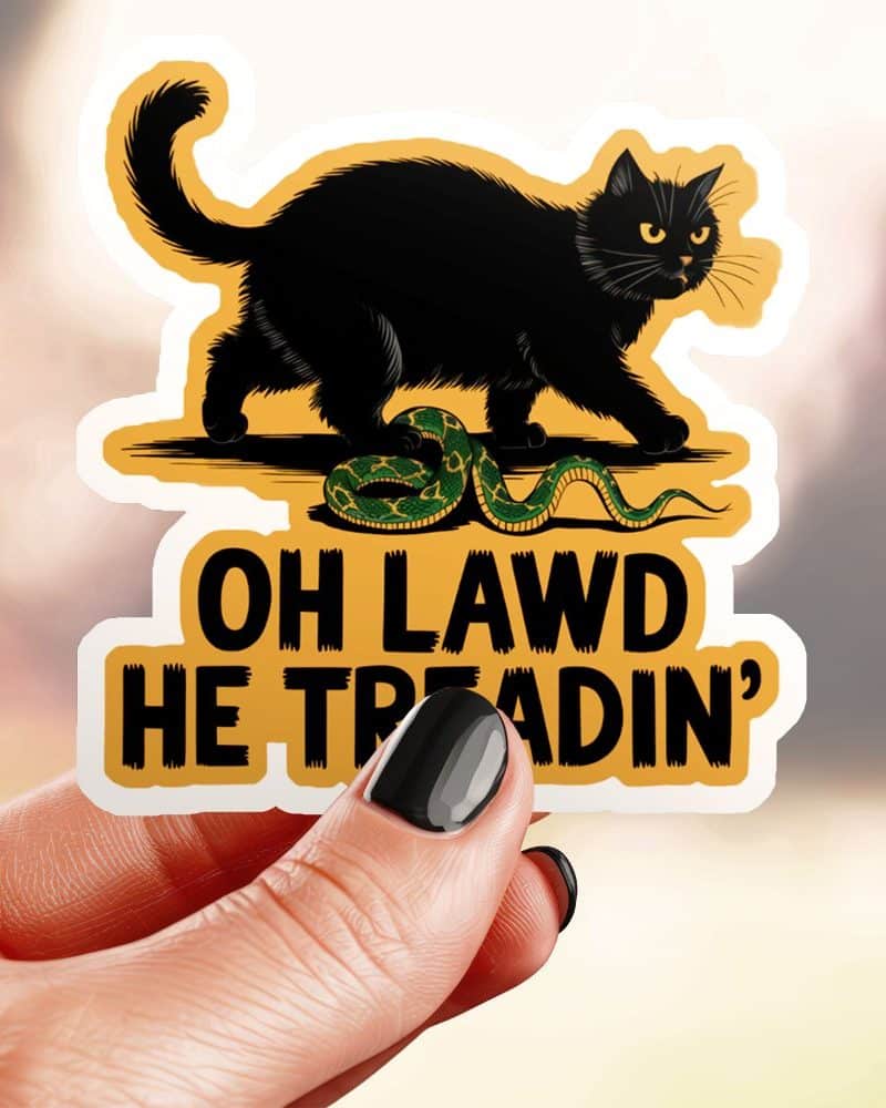 Sticker of a black cat standing over a snake with the text Oh Lawd He Treadin'.