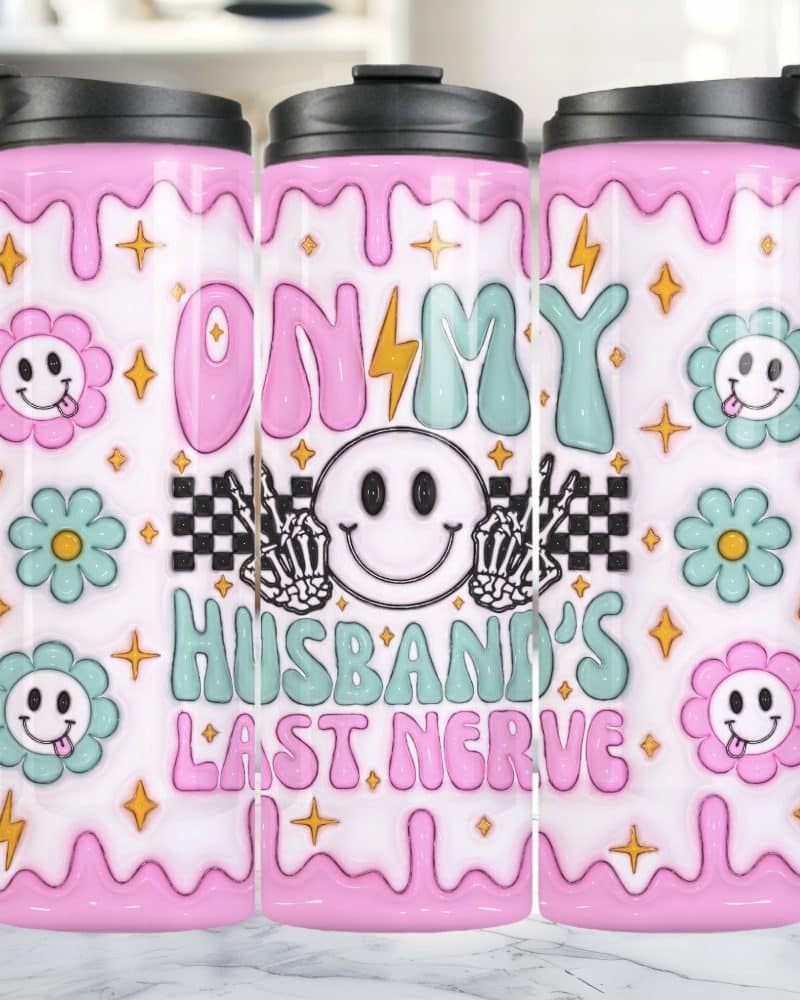 Three pink travel mugs with a playful design featuring a smiling face, flowers, and the text "On My Husband's Last Nerve".
