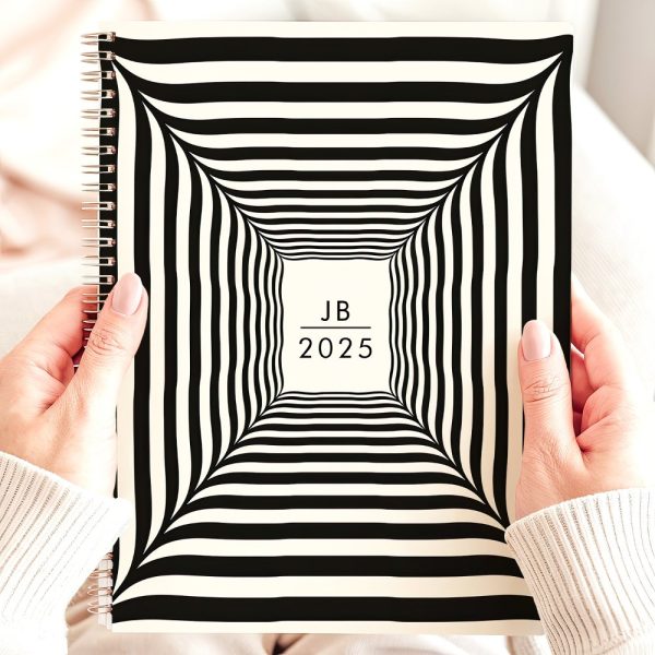 Hands Holding A 2025 Spiral-Bound Notebook With A Black And White Striped, Tunnel-Like Design And The Initials Jb.