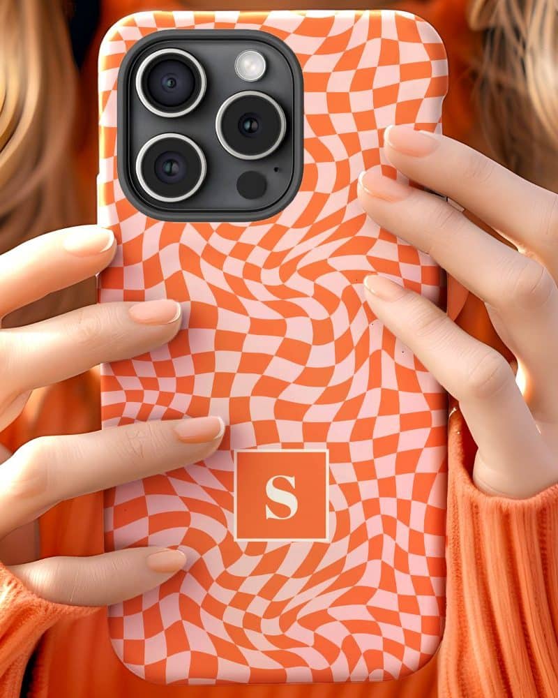 Close up of hands holding an orange and white checkered phone case with a letter S in the center.