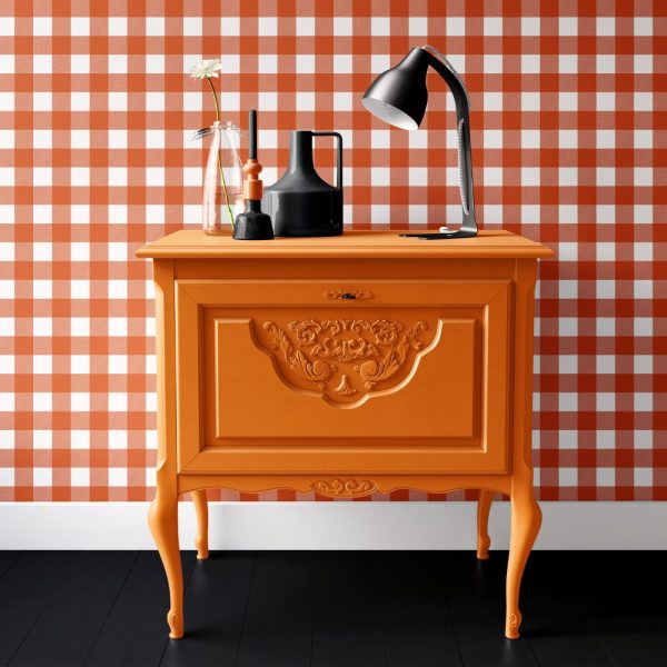 Orange Painted Wood Cabinet With Ornate Details, Holding A Lamp And Decorative Objects.