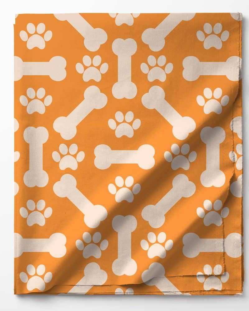 Orange fabric with a repeating pattern of white bones and paw prints.