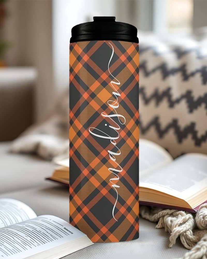 Personalized orange and black plaid tumbler with the name Madison.