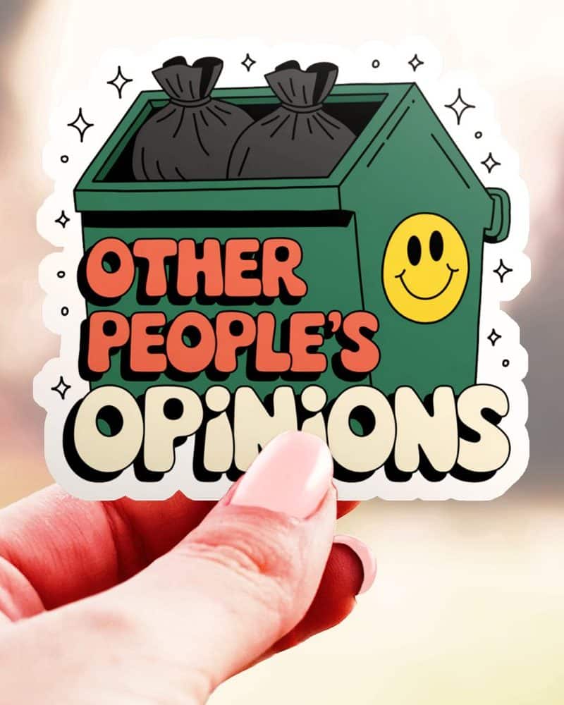 Hand holding a sticker of a dumpster with garbage bags inside, and the text "Other People's Opinions" below it. A smiley face is on the dumpster.