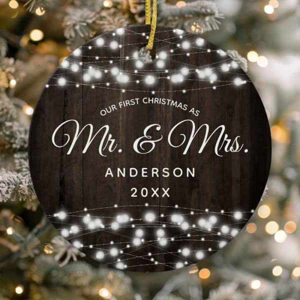 Round Christmas Ornament With Dark Wood Background, String Lights, And The Text Our First Christmas As Mr. &Amp; Mrs. Anderson 20Xx.