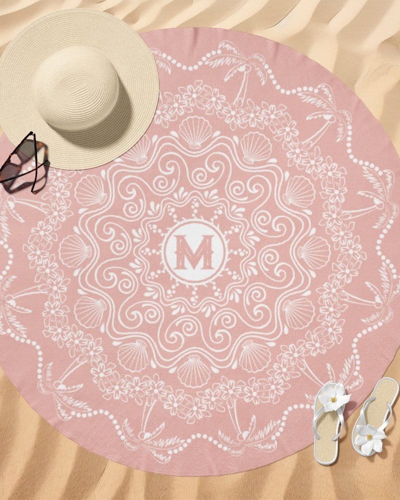 Pink round beach towel with a white mandala design and a monogrammed M in the center.