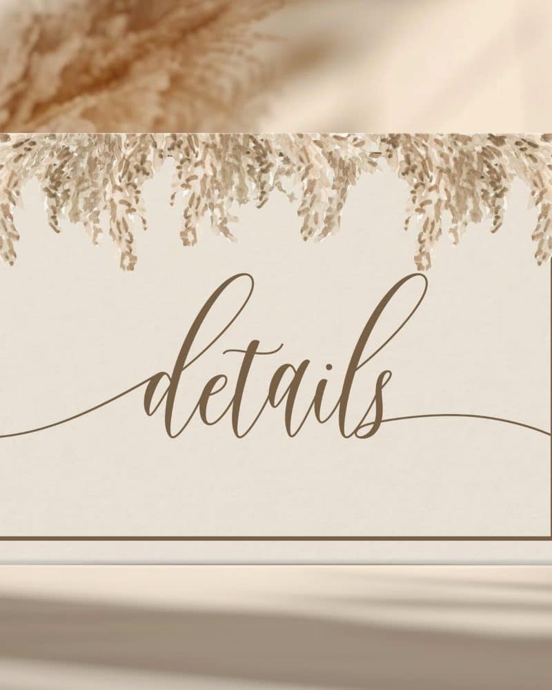 Beige sign with brown border and script lettering that says Details, decorated with a tan floral garland at the top.