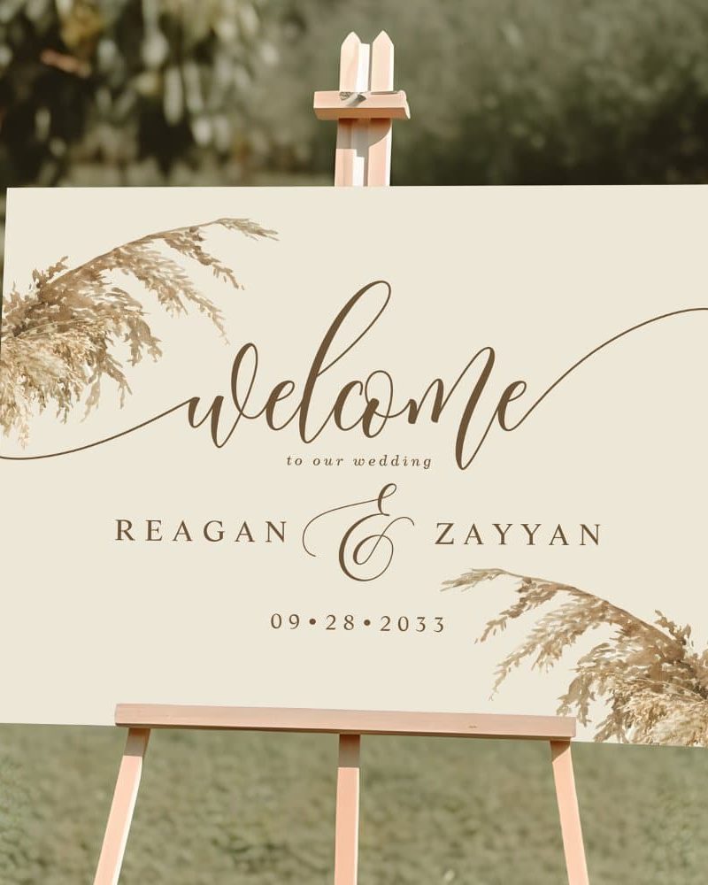 Beige wedding welcome sign with pampas grass design, announcing Reagan and Zayyan's wedding on September 28, 2033.