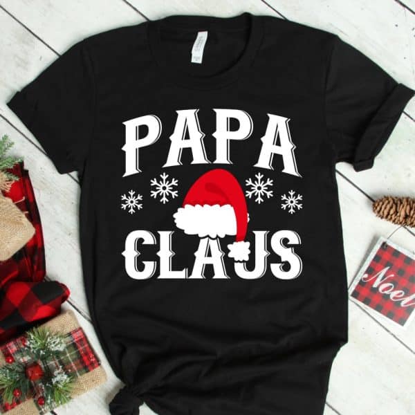 Black T-Shirt With Papa Claus Design Featuring A Santa Hat And Snowflakes.