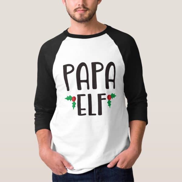 Man Wearing A White And Black Baseball Tee That Says Papa Elf With Holly Berries.