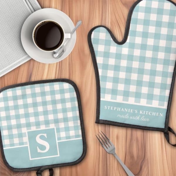A Pair Of Light Blue Gingham Oven Mitts And Pot Holder, Personalized With A Name And Initial.