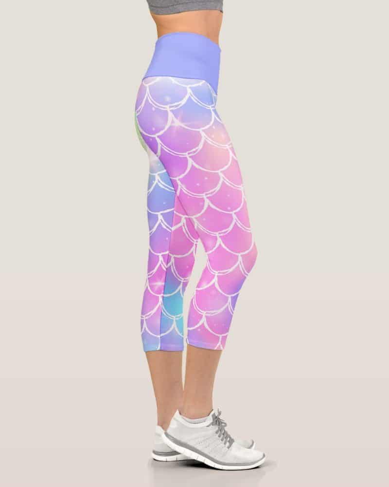 Woman's legs wearing pastel mermaid-scale patterned cropped leggings and white athletic shoes.