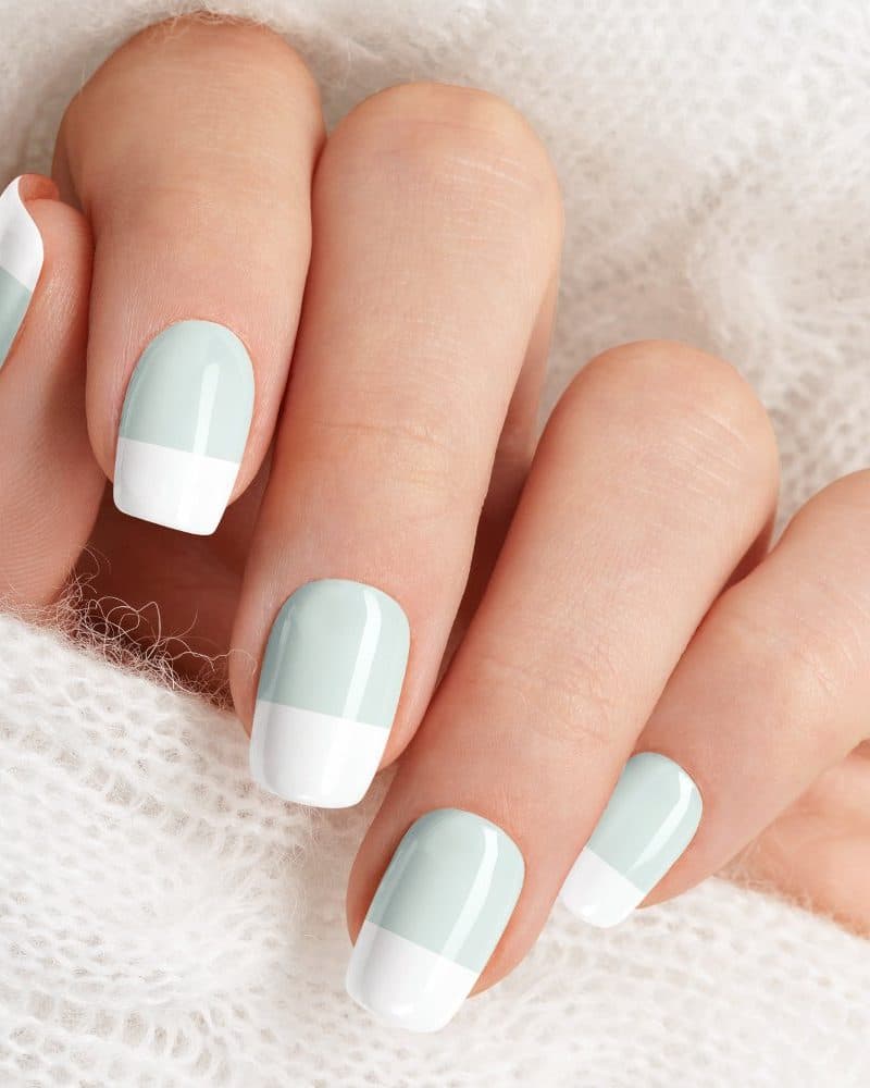 Hand with light blue and white half-moon manicured nails.